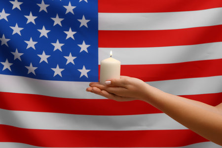 Woman holding burning candle on USA flag background. National Day of Prayer and Remembrance for the Victims of the Terrorist Attacks.の写真素材