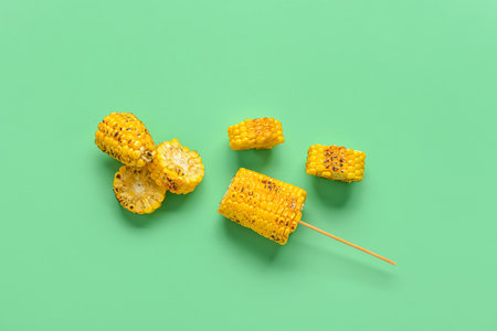 Cut tasty grilled corn cobs on green backgroundの写真素材