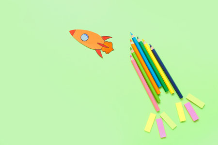 Pencils and stickers with paper rocket on green backgroundの写真素材