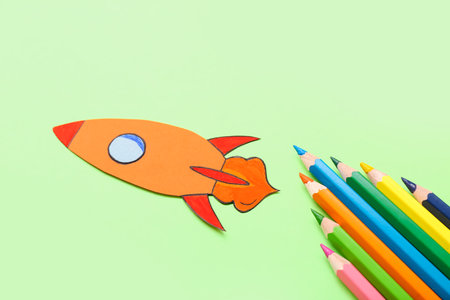 Pencils with paper rocket on green backgroundの写真素材