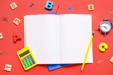 Different school stationery and blank notebook on red background
