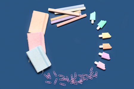 Frame made of stylish notebooks and markers in different shapes on blue backgroundの写真素材
