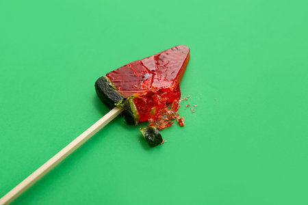 Lollipop in shape of watermelon slice on green backgroundの写真素材
