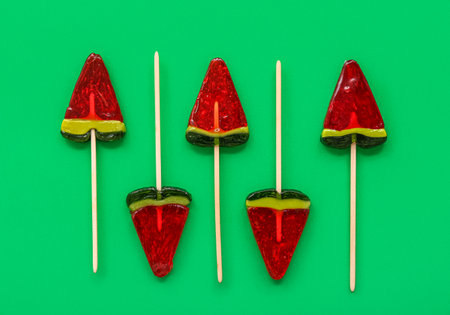 Lollipops in shape of watermelon slice on green backgroundの写真素材