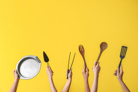 Female hands with baking utensils on yellow backgroundの写真素材