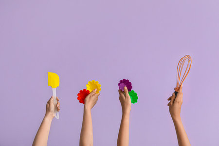 Female hands with baking utensils on lilac backgroundの写真素材