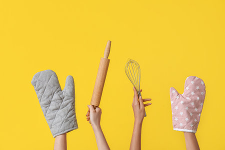 Female hands with baking utensils on yellow backgroundの写真素材