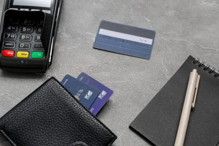Payment terminal with wallet and credit cards on grunge gray background