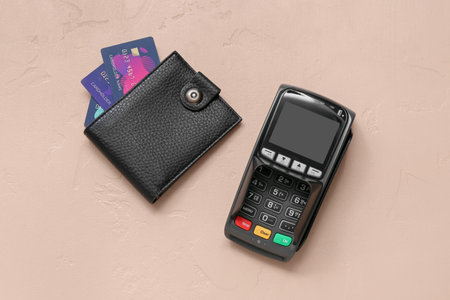 Leather wallet with credit cards and payment terminal on brown background