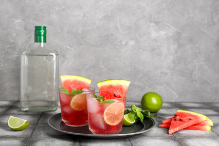 Glasses of tasty watermelon cocktail with lime and mint on grunge gray table near wallの写真素材