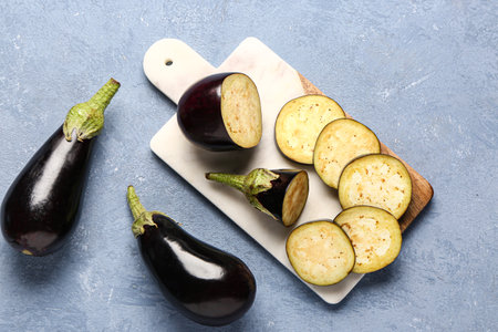 Board with fresh eggplants and cut slices on blue backgroundの写真素材