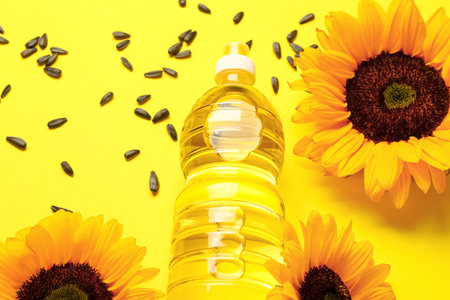 Sunflowers, seeds and bottle of oil on yellow backgroundの写真素材