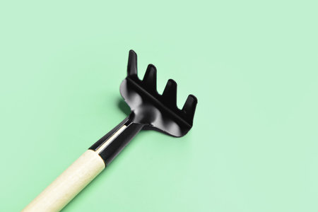 Gardening rake on green background