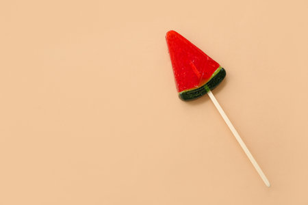 Lollipop in shape of watermelon slice on beige backgroundの写真素材