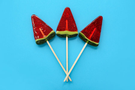 Lollipops in shape of watermelon slice on blue background