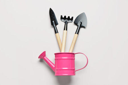 Watering can with gardening rake and shovels on white backgroundの写真素材