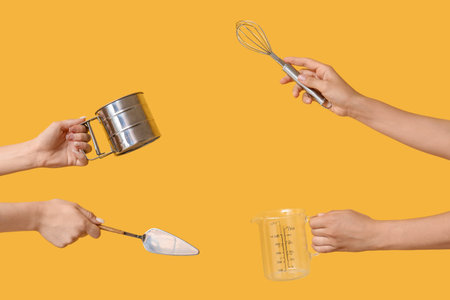 Female hands with baking utensils on yellow background