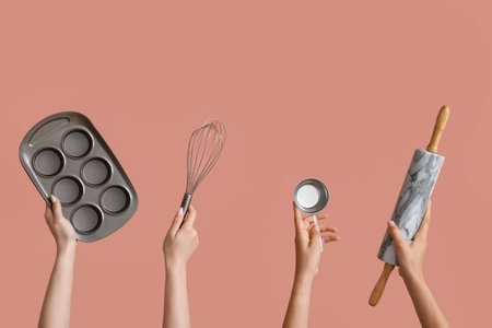 Female hands with baking utensils on pink background