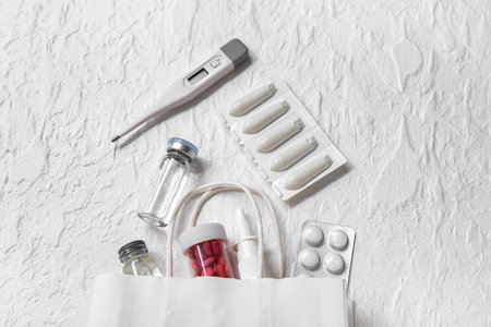 Shopping bag with different pills and thermometer on white textured background