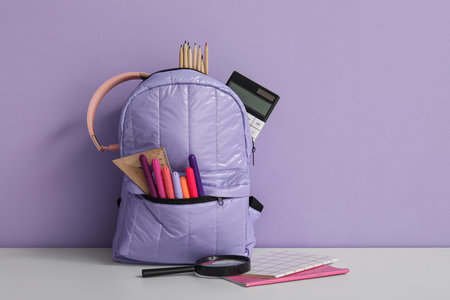School backpack with different stationery and headphones on white table near purple wallの写真素材