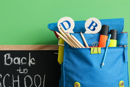 School backpack, different stationery and blackboard with text BACK TO SCHOOL on green backgroundの写真素材