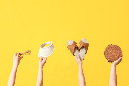 Many hands holding beach accessories on yellow backgroundの写真素材