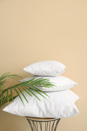 Table with white pillows and houseplant near beige wallの写真素材