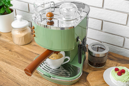 Modern coffee machine with cup of hot espresso and cake on table in kitchenの写真素材