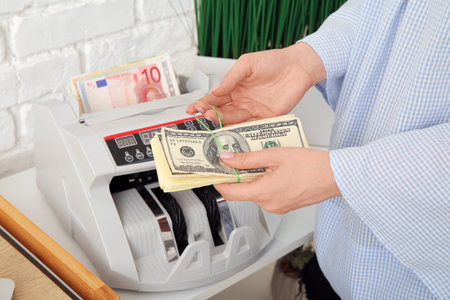 Woman counting money near cash register on shelf in office, closeupの写真素材
