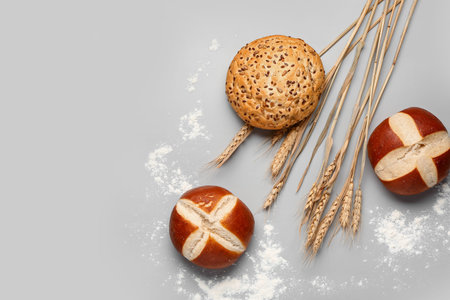 Fresh buns and wheat ears on gray background