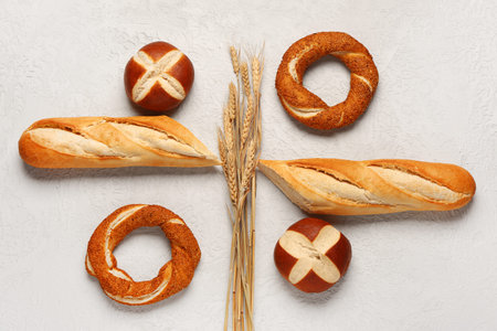 Composition with different types of bread and wheat ears on white table