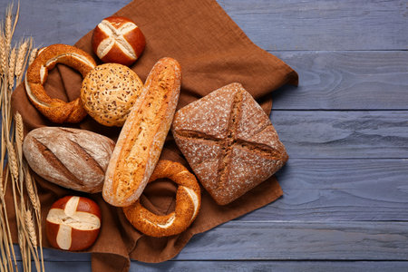 Different types of bread and wheat ears on blue wooden tableの写真素材
