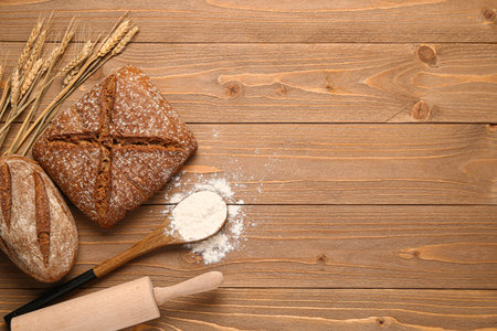 Loaves of fresh rye bread and wheat flour on wooden table