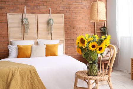 Vase with beautiful sunflowers on wicker chair in interior of stylish bedroomの写真素材