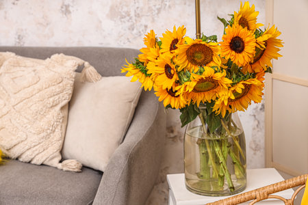 Vase with beautiful sunflowers on table in interior of light living room, closeupの写真素材