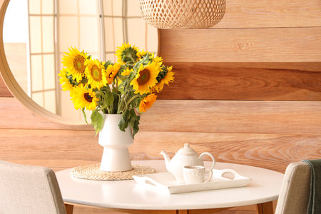 Vase with beautiful sunflowers on dining table with teapotの写真素材