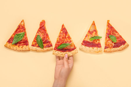 Woman taking slice of tasty pizza on yellow backgroundの写真素材