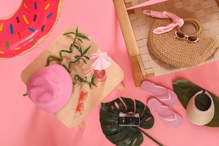 Beach accessories, bottle of drink and chair on pink background