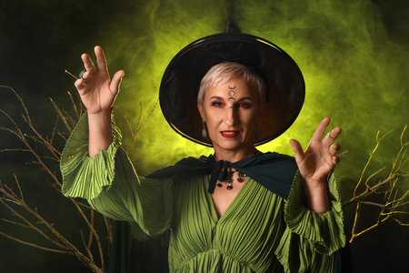 Mature witch with tree branches and green smoke on dark background