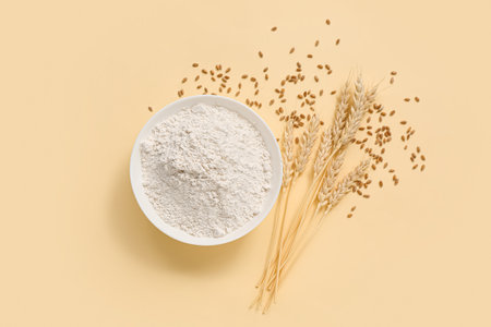 Bowl with wheat flour and spikelets on yellow backgroundの写真素材