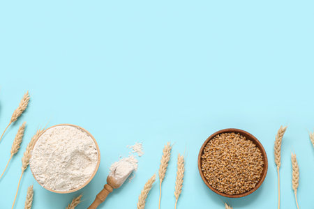 Bowls with wheat flour, grains and spikelets on blue backgroundの写真素材