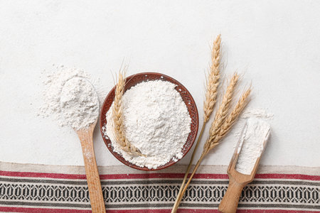 Wooden bowl, scoop and spoon with wheat flour on white backgroundの写真素材