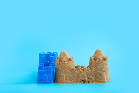 Castle made of sand with beach toy on blue backgroundの写真素材