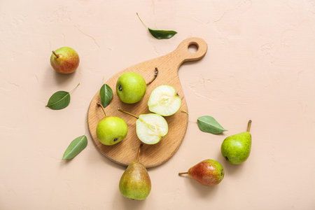 Wooden board with ripe pears on beige table