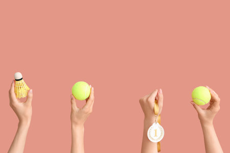Female hands with tennis balls, shuttlecock and medal on pink backgroundの写真素材