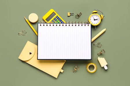 Notebook with different stationery supplies on green background