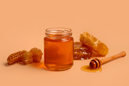 Jar with sweet honey and combs on orange background