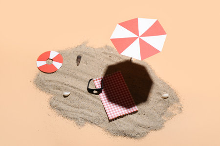 Creative summer composition with mini umbrella, beach accessories and sand on beige backgroundの写真素材