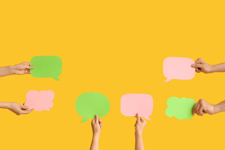 Different hands with speech bubbles on yellow backgroundの写真素材