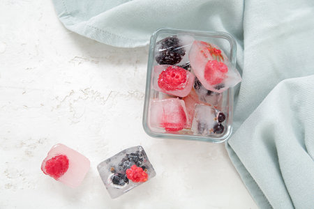 Glass bowl with frozen berries in ice cubes on white backgroundの写真素材